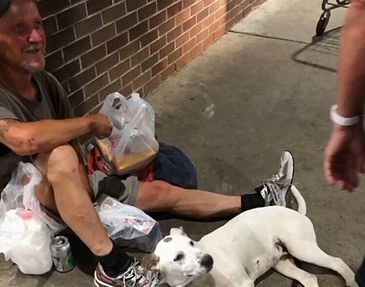 地面に座り笑顔を見せるホームレスのアンソニーさんと愛犬のボボ